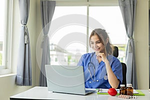 Female doctor chats online with patient Attractive female doctor working remotely from hospital in office