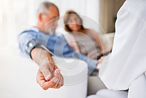 Female doctor checking blood pressure of senior man.