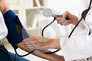 Female doctor checking blood pressure of senior woman, closeup