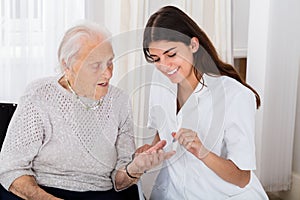 Female Doctor Checking Blood Sugar Level Of Senior Patient