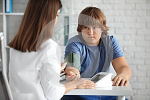 Female doctor checking overweight boy`s blood pressure