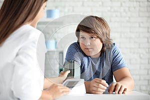 Female doctor checking overweight boy`s blood pressure