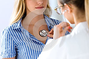Female doctor checking patient heartbeat using stethoscope.