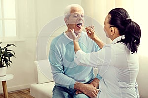 Female doctor checking throat of senior man