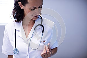 Female doctor checking time on pocket watch