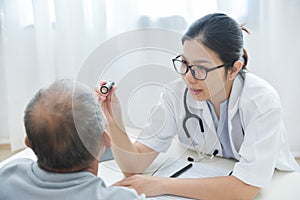 Female Doctor checking to senior man patient eyes.