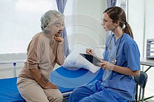 Female doctor with clipboard talking with elderly female patient at hospital Senior woman or doctor