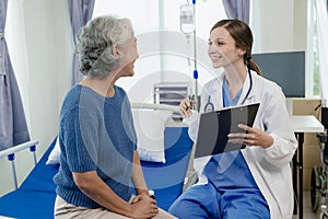 Female doctor with clipboard talking with elderly female patient at hospital Senior woman or doctor