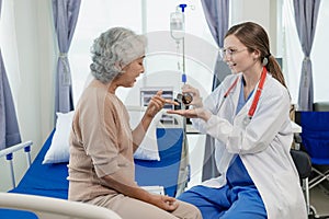 Female doctor with clipboard talking with elderly female patient at hospital Senior woman or doctor