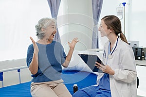 Female doctor with clipboard talking with elderly female patient at hospital Senior woman or doctor