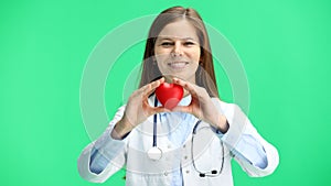 Female doctor, close-up, on a green background, shows a heart