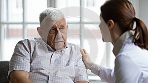 Female doctor comforting upset older patient at meeting