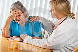 Female Doctor Consoling Distraught Senior Adult Woman