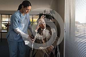 Female doctor consoling sad disable senior man at nursing home