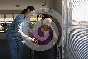 Female doctor consoling sad disable senior woman at nursing home