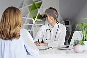 Female doctor consulting her patient while sitting at desk in doctor`s office photo