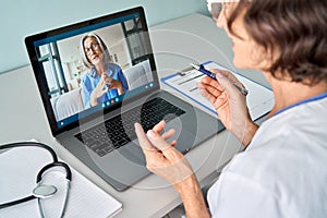 Female doctor consulting older senior patient during virtual video call visit. photo