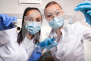 Female doctor dentist and assistant in masks looking at camera photo