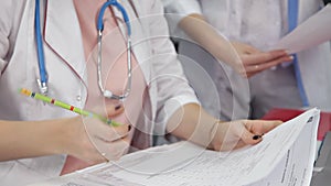 Female doctor doing paperwork in the office. Young therapist filling medical checklist sitting at the desk. Health care