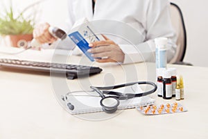 Female doctor entering medication information into computer, there are various drugs on table