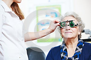 Female doctor examines senior woman eye sight with phoropter photo