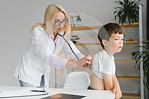 Female doctor examining boy by stethoscope