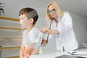 Female doctor examining boy by stethoscope