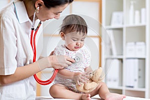 Female doctor examining child toddler with stethoscope
