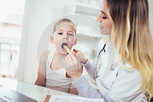 Female doctor examining child with tongue depressor