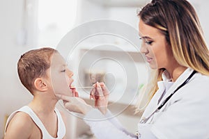 Female doctor examining child with tongue depressor