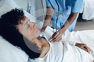 Female doctor examining female patient with stethoscope in the ward