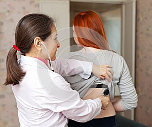 Female doctor examining girl with stethoscope