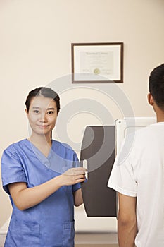 Female Doctor Examining Male Patient's Mid Section With X-ray Machine