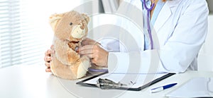 Female doctor examining a nTeddy bear patient by stethoscope. photo