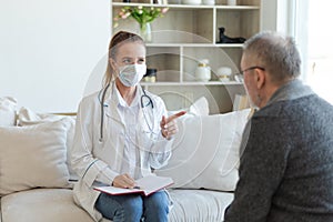 Female doctor examining older senior man in doctor office or at home. Old man patient and doctor have consultation in