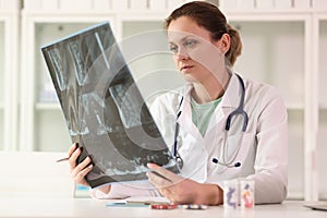Female doctor examining x-ray scan film of patient while sitting at hospital.