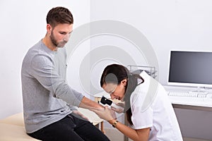 Female Doctor Examining Skin Of Male Patient