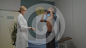 Female doctor examining young male patient using stethoscope indoors
