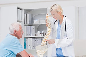 Female doctor explaining anatomical spine to senior man