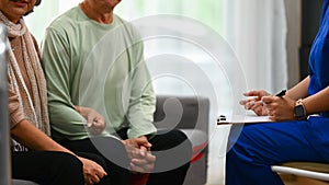 Female doctor explaining therapy details to mature man during home visit. Elderly healthcare concept