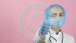 Female doctor in face mask and medical gloves showing hand gesture thumbs up