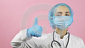 Female doctor in face mask and medical gloves showing hand gesture thumbs up