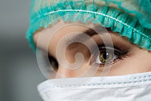 Female doctor face wearing protective mask and green surgeon cap