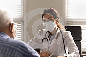 Female doctor in facemask consult mature patient