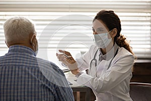 Female doctor in facemask consult senior patient