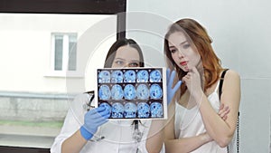 A female doctor and a female patient discuss a ct scan of the brain in the doctor's office. Doctor's