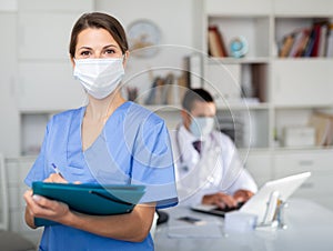 Female doctor filling out medical form on clipboard