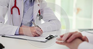 Female doctor filling out medical history list on clipboard notepad