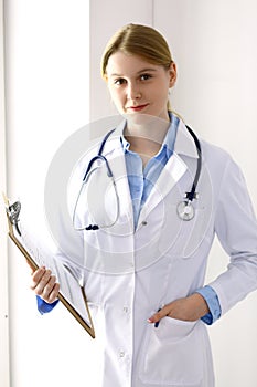 Female doctor filling up medical form on clipboard closeup. Physician finishing up examining his patient in hospital an