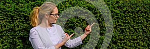 Female doctor with fingers point up. Nutritionist in white coat and glasses on natural background with copy space. Image for